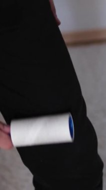 Tişörtten tüy ve yünü pamuklu bir rulo ile çıkarıyor. Kıllı silindir tutan adam..