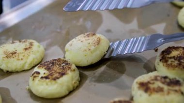 Kızarmış peynirli kekler aşama aşama pişiriliyor. Eller kaymak toplarını yuvarlar. Peynirli kekler tavada kızartılır. Lezzetli yemekler hazırlama süreci. Cheesecake veya cheesecake. Sağlıklı yemek.