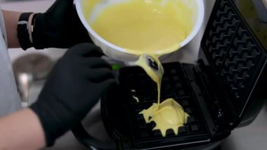 Elektrikli waffle makinesinde ev yapımı waffle yapmak. Kahvaltı şefi unu karıştırıyor, yumurta çırpıyor waffle yapmak için hamur pişiriyor, krep yapıyor. Sabah kahvaltısı, yemek hazırlama, yemek tarifi...