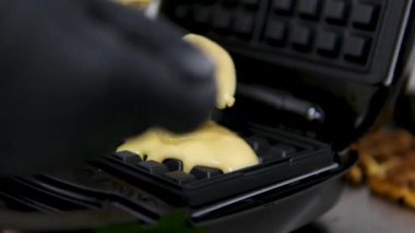 Elektrikli waffle makinesinde ev yapımı waffle yapmak. Kahvaltı şefi unu karıştırıyor, yumurta çırpıyor waffle yapmak için hamur pişiriyor, krep yapıyor. Sabah kahvaltısı, yemek hazırlama, yemek tarifi...