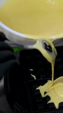 Elektrikli waffle makinesinde ev yapımı waffle yapmak. Kahvaltı şefi unu karıştırıyor, yumurta çırpıyor waffle yapmak için hamur pişiriyor, krep yapıyor. Sabah kahvaltısı, yemek hazırlama, yemek tarifi...