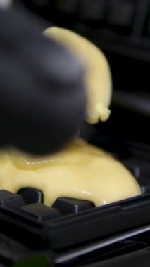 Elektrikli waffle makinesinde ev yapımı waffle yapmak. Kahvaltı şefi unu karıştırıyor, yumurta çırpıyor waffle yapmak için hamur pişiriyor, krep yapıyor. Sabah kahvaltısı, yemek hazırlama, yemek tarifi...