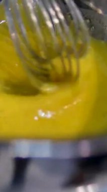 Hollandaise soslu Benedict usulü yumurta. Hollandaise sosunu metal bir kaşıkla güveçte harmanlamak.