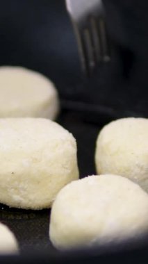 Kızarmış peynirli kekler aşama aşama pişiriliyor. Eller kaymak toplarını yuvarlar. Peynirli kekler tavada kızartılır. Lezzetli yemekler hazırlama süreci. Cheesecake veya cheesecake. Sağlıklı yemek.