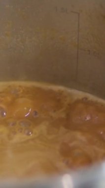 Karamel sosu pişir. Baloncuklu kaynamış şeker karamelaya, karamelizasyona dönüşür. Makro atış. Yavaş çekim.