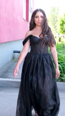 Siyah uzun elbiseli kız. Uzun esmer saçlar rüzgârda uçuşuyor. Dalgalı kıvırcık saç stili. Siyah akşam modasına uygun balo elbisesi. Güzellik güçlü yüz zarif makyaj