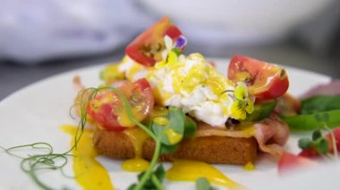 Sağlıklı sabah yemeği. Kahvaltıda lezzetli haşlanmış yumurta yemek. Erkek elleri, yumurtanın içinde yumurta sarısı, hollandaise sosu ve İngiliz çöreğine ıspanak olan Benedict yumurtalarını keser. Kapat.