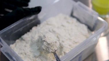 Dişi bir fırıncı taze pişmiş yiyecekler yapmak için hamuru yoğurmak için özel bir kaşıkla buğday unu topluyor. Kaşıkla un kepçesi