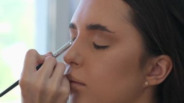 Göz makyajına rimel süren mutlu genç bir kadın sabah hazırlanıyor, gülümsüyor makyaj yapıyor makyaj yapıyor, makyaj yapıyor evdeki banyoda aynaya bakıyor.