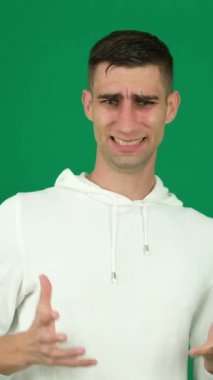 Öfke saldırganlığı. Yeşil arka planda yakışıklı bir adamın duyguları... Kromakey yakın plan koyu saçlı genç adam... Öfkeli Amerikalı adam....