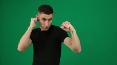 Boks pozu veren adam. Yeşil arka plan krom renkli, yakın plan koyu saçlı yakışıklı bir adamın duyguları. Genç adam heyecanlı sporcu boksör boksör golü için poz veriyor. sağlıklı yaşam tarzı