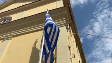Yunanistan siyaseti ve haberleri. Sarı bina arka planında Yunan ulusal bayrağı 