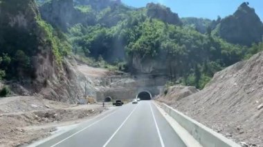 Arnavutluk dağları. Arnavutluk 'ta dağ zirvelerinde bulutlar dolaşıyor. Sürücü arabaların penceresinden görüntüler