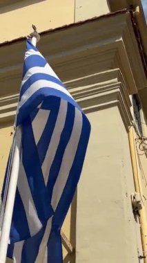 Yunanistan siyaseti ve haberleri. Sarı bina arka planında Yunan ulusal bayrağı 