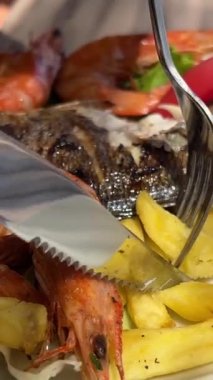 Arnavutluk 'ta bir restoranın sokağında Dorado balığı, patates kızartması ve karides. Restoranda Dorado balığı. Sebze soslu fırında dorado balığı ve ızgara sebze.