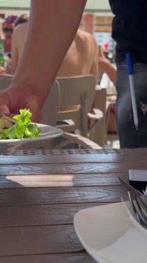 Garson dorado balığı servis ediyor. Aşçı mutfakta dorado pişiriyor.