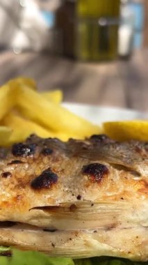 Garson dorado balığı servis ediyor. Aşçı mutfakta dorado pişiriyor.