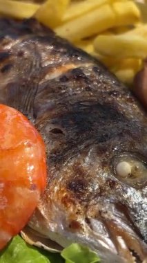 Arnavutluk 'ta bir restoranın sokağında Dorado balığı, patates kızartması ve karides. Restoranda Dorado balığı. Sebze soslu fırında dorado balığı ve ızgara sebze.