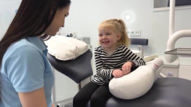 Learning about oral and dental hygiene. Dentist examining little girls teeth and mouth during dental appointment. Child looking in mirror and having her checkup to prevent tooth decay and gum disease