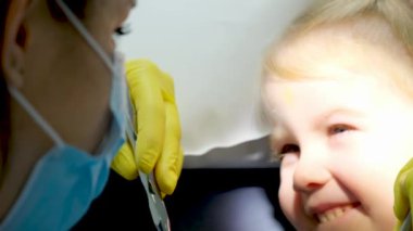 Ağız ve diş temizliğini öğreniyorum. Diş hekimi, dişçi randevusu sırasında küçük kızların dişlerini ve ağızlarını muayene ediyor. Çocuk aynaya bakıyor ve diş çürümesi ve sakız hastalığını önlemek için onu kontrol ettiriyor.