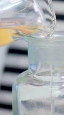 Kadınların ellerini kapağına çamaşır deterjanı dökerken beyaz köy masasına hasır sepetin içinde havlularla kapatın. Şişeye sıvı dök.