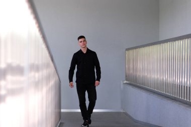 Genç işadamı uzun ofis koridoru boyunca gidiyor. Kamera arkası pencereli. Takım elbiseli bir adam işe gitmek için salonda yürüyor. Ofis stili oluşturma başarılı