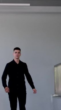 Genç işadamı uzun ofis koridoru boyunca gidiyor. Kamera arkası pencereli. Takım elbiseli bir adam işe gitmek için salonda yürüyor. Ofis stili oluşturma başarılı