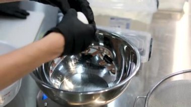 Ev yapımı mutfak. Aşçı elleri tavuk yumurtalarını metal bardakta kırar. Yakın plan. Bir kaseye yumurta kır.