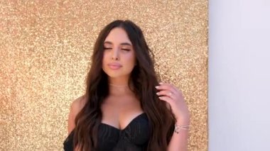 Altın arka planda siyah saçlı kız. Siyah elbiseli Arap kız. Fantezi seksi kadın, odada, güzel prenses. Manken kız aşkı bekliyor. Siyah altın uzun elbise. Eski tarz sanat videosu