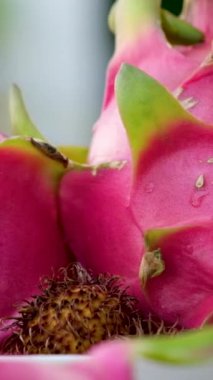 Pembe arka planda izole edilmiş bir tabakta iki yarım ejderha meyvesi Pitahaya..