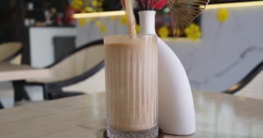 Çikolatalı süt bardağa dökülüyor, akarken sıçrıyor, masaya dökülüyor. Çikolatalı milkshake.