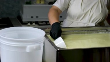 Çiftçi kadın süt çiftliğinde süt sağmak için konteyner tankına çiğ süt döküyor. Kariyer tarımı. Ağır çekim. Gerçek inekler Asya Tayland 'da süt sağar. Çiğ süt