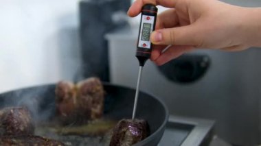 Sığır filetosu bifteği hazırlama işlemi. Yavaş çekimde dumanlı tavada baharatlı ve otlu sulu et bifteği yakın çekim. Meyveli biftek piknik kutlaması için hazır. Barbekü