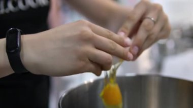 Yumurta kırıyorum. Kırık bir yumurtayı tutan kadın eller. Yumurta kırıyorum. Siyah arka plan. Yavaş çekim.