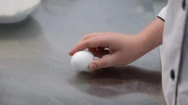 Yumurta kırıyorum. Kırık bir yumurtayı tutan kadın eller. Yumurta kırıyorum. Siyah arka plan. Yavaş çekim.