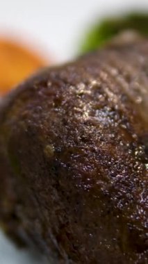 Sığır filetosu bifteği hazırlama işlemi. Yavaş çekimde dumanlı tavada baharatlı ve otlu sulu et bifteği yakın çekim. Meyveli biftek piknik kutlaması için hazır. Barbekü