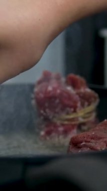 Sığır filetosu bifteği hazırlama işlemi. Yavaş çekimde dumanlı tavada baharatlı ve otlu sulu et bifteği yakın çekim. Meyveli biftek piknik kutlaması için hazır. Barbekü