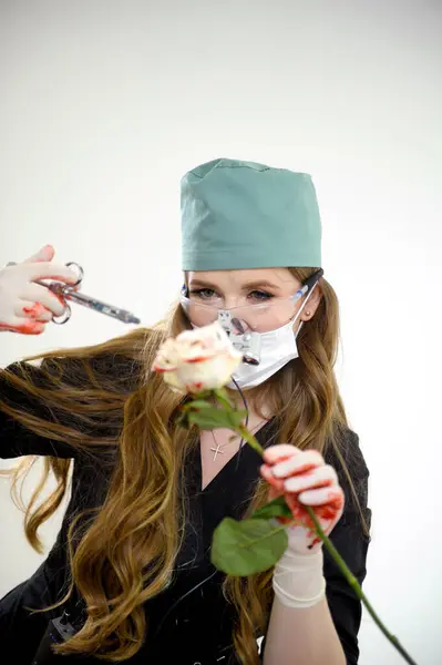 stock image Young woman learning to operate on a flower on a rose using a scalpel and an injection. Operation on the layout . 