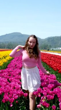 Güzel Hollanda lale tarlasında güneşlenen süslü bir kadın. Güneşli yaz gününde şapkasını çıkaran neşeli bir kadın. Bahar çiçeklerinin bahçesinde yüzü güneşe dönen rahat bir kız. Lale tarlasında bir kız