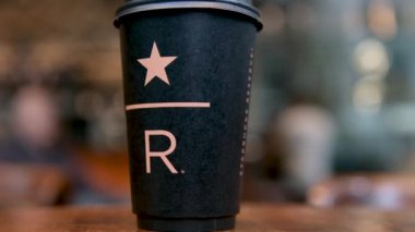 Starbucks Resort siyah Starbucks bardağı. Kahve dükkanının masasında üzerinde büyük harfli R harfi var. Lezzetli, yeni, lüks kahve markası. en yeni