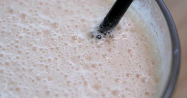 Dalgona kahvesi, çırpılmış hazır kahve ve sağlıklı protein barlı tahta bir tahtanın üstünde sütle kokteyl. Vanilyalı frappe. Şeker şurubu