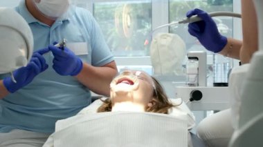 Dişçi dolgusu. Kadın dişçi, dişçi kliniğinde genç kız hastaların dişlerini muayene ediyor. Bir kaşif kullanarak dişleri sondajlayan doktor çürük tedavisi ve kontrol için