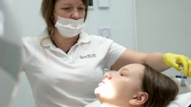 Dentist filling. female dentist examining young girl patients teeth at dental clinic. Doctor probing teeth with dental instrument using an explorer look for cavities treatment and checking