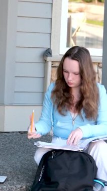 Verandadaki sevimli öğrenci kız. Üniversitenin yakınında gülümseyen genç bir kız. Sevimli kız öğrenci kitapları tutuyor. Öğrenme, eğitim kavramı