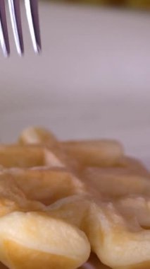 Çatal ve bıçakla çırpılmış kremayla kaplı Belçika waffleları kesen kadın elleri. Yüksek kalite 4k görüntü