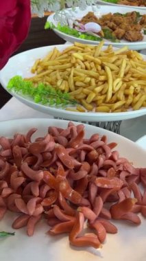Yiyecek beyaz tabakta sunulur. Açık büfe patates sosis hamurda kızartılmış donut balığı. 