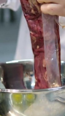 Şef mutfak masasının önünde bıçağını biliyor. Aşçı çiğ et ve çeşitli sebze filetosu kesmeden önce aletlerini hazırlıyor. Çiğ biftek kesimi.