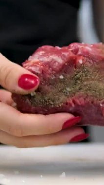 Bir kızda kırmızı manikür. Çiğ domuz eti dilimlerinin üzerine yeşil kekik serpiyorum. Etin üzerine kara biber serp