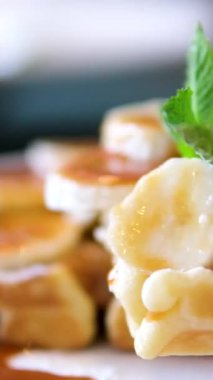 Muzlu waffle ve karamelli beyaz gömlek muz ekmeği waffle 'ının üzerine tatlı şurup döküyor..