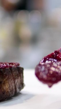 Şef vişne soslu kırmızı biftek pişiriyor, yakın plan. Tatlı soslu doğranmış et ve tabakta sebze. Avrupa Mutfağı Yıldız Anason. Et için kiraz sosu.